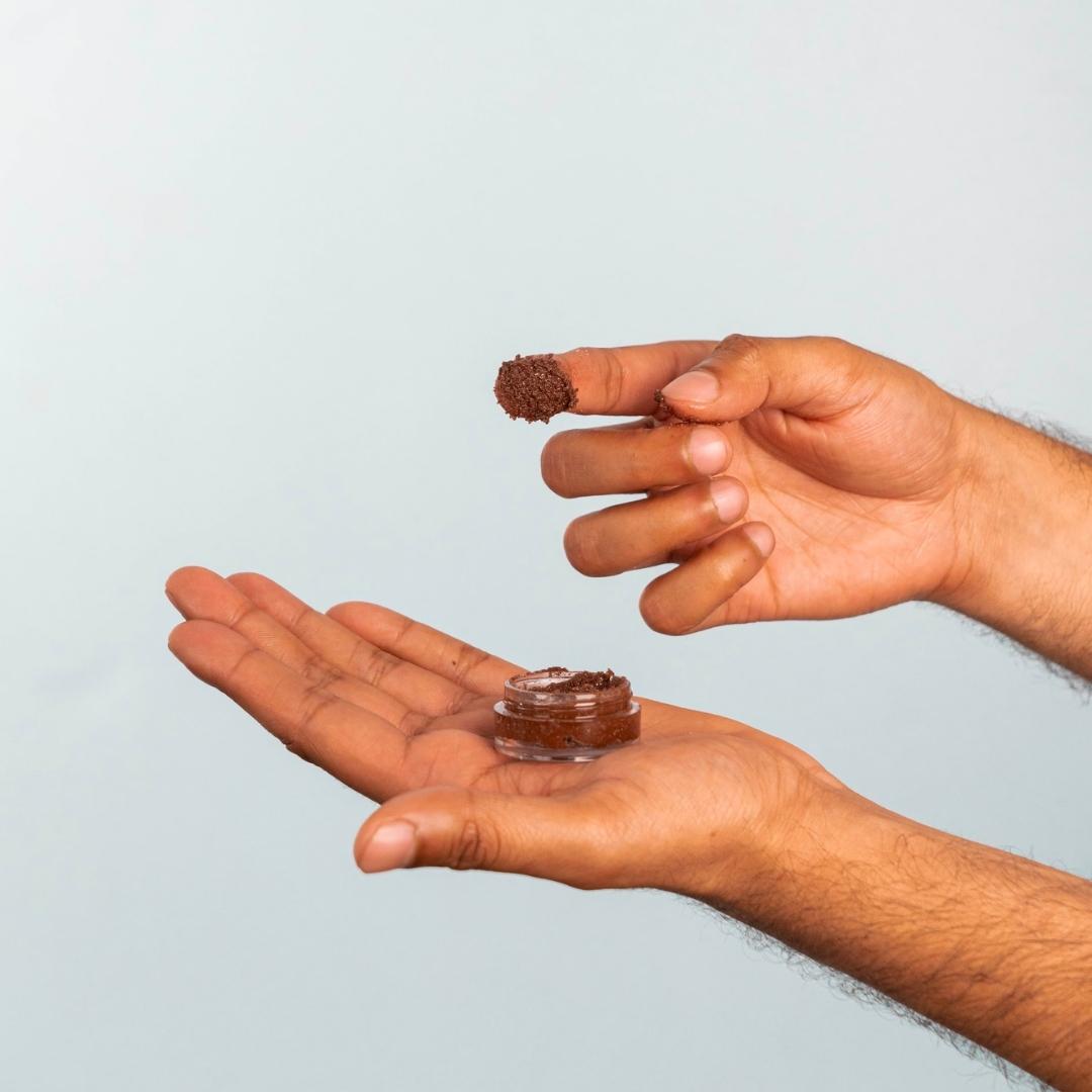 A scoop of chocolate lip scrub from the container